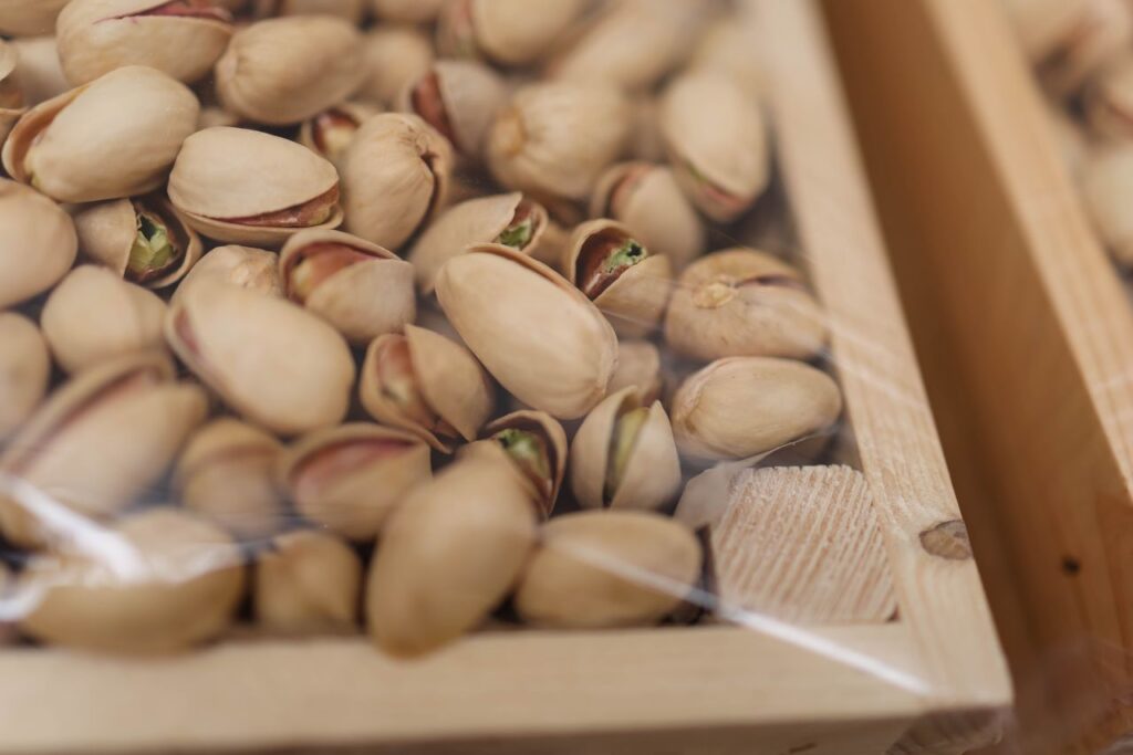 A detailed close-up shot of unshelled pistachios in a wooden box, perfect for food photography.